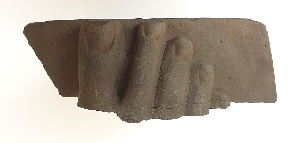 Fuß eines stehenden Buddha (Fragment). Sockelrelief: zwei Mönche unter Akanthusblattfries