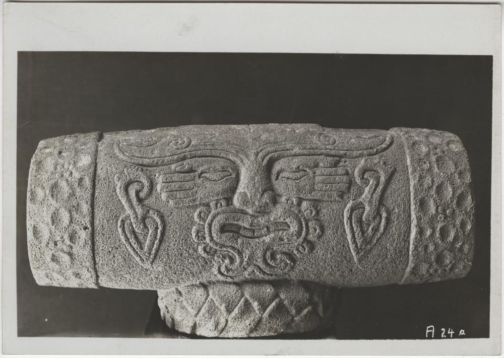 Antike Steinnachbildung eines auf einem Bastkringel ruhenden Teponaztli (Holztrommel) mit Reliefdarstellung auf den Spiel- und Tanzgott (Blumengott) Macuilxochitl bezüglich.  Sammlung Guillermo de Heredia.