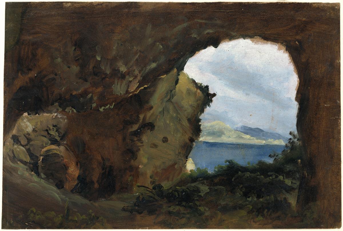 Blick aus einer Felsenhöhle auf Meer und Berge
