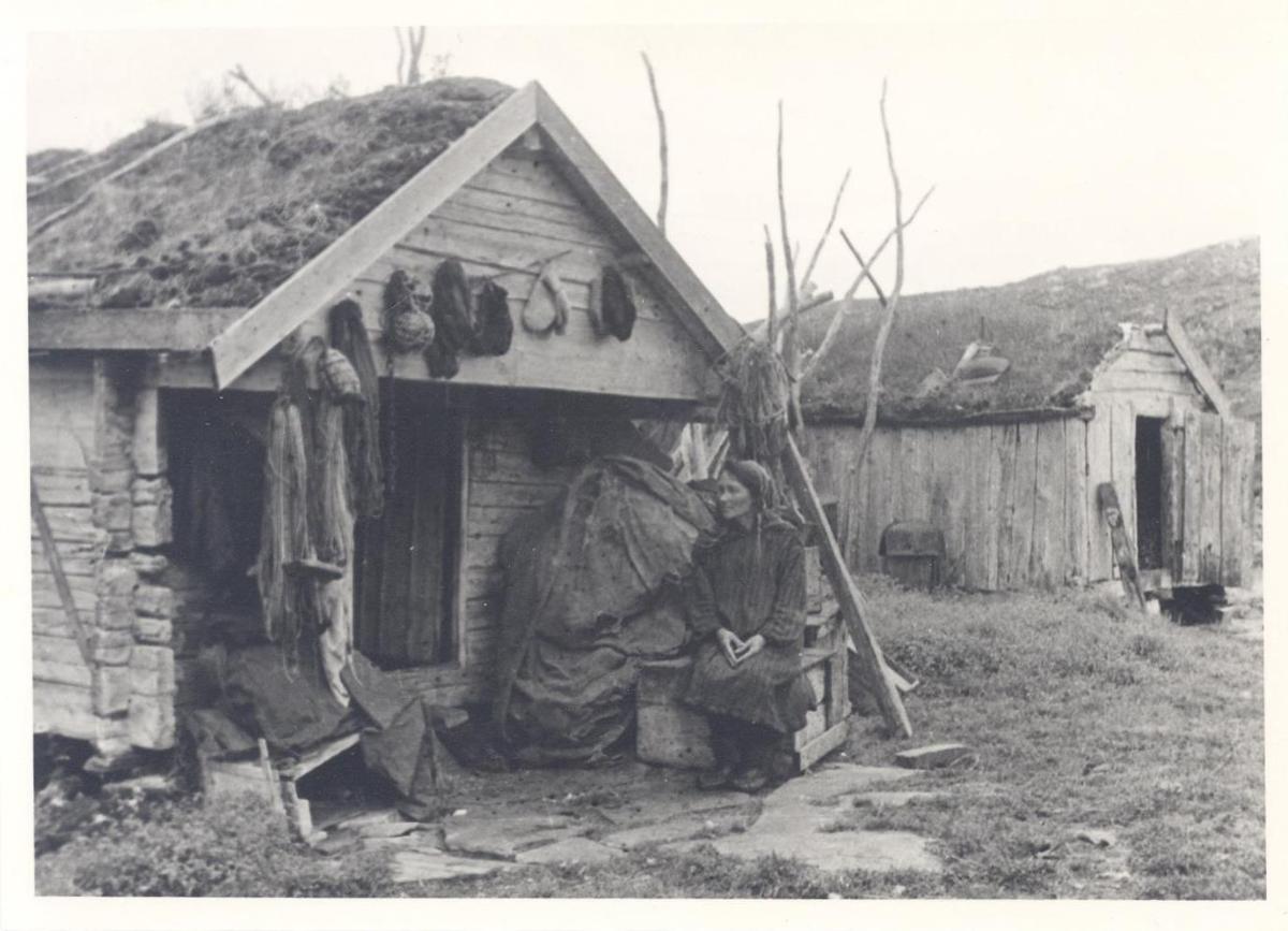 Samin vor einem Holzhaus