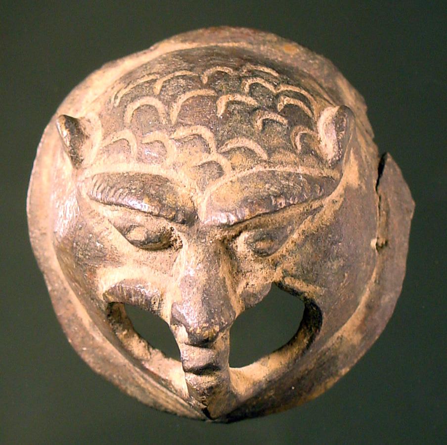 Runde, stilisierte Löwenmaske mit doppelt durchbohrtem Maul
