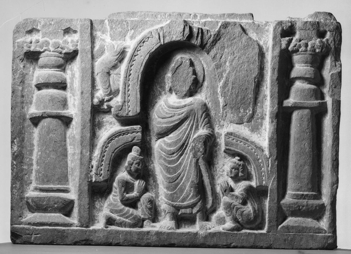 Stehender Buddha mit Ellbogen im Gewand unter Chaitya-Bogen mit zwei Verehrern