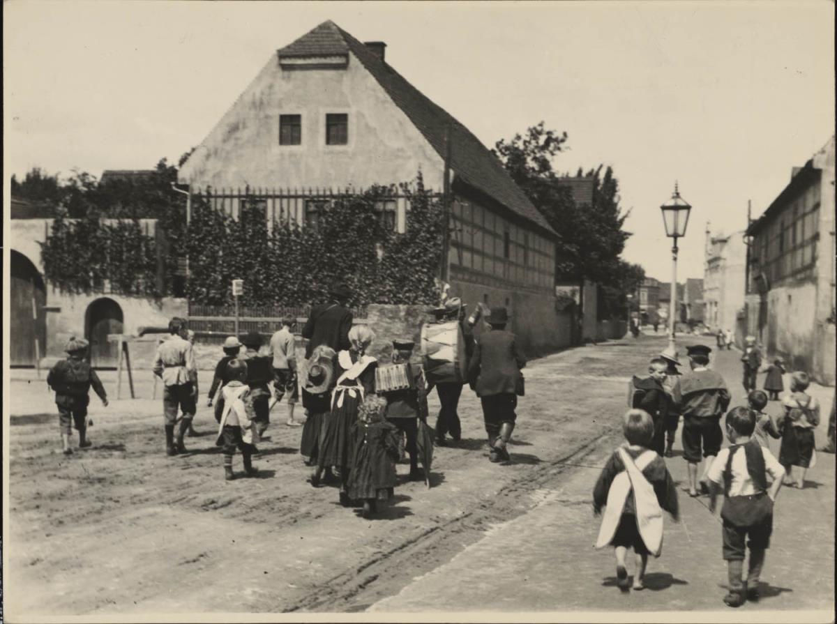 Musikanten und Kinder gehen durch das Dorf, Coswig