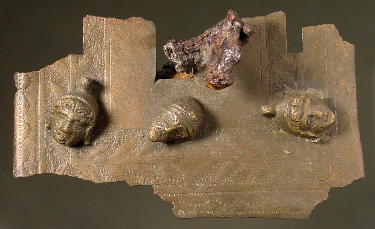 Fragmentiertes Schlossblech eines römischen Kästchens mit Maskenappliken und einem großen Teil des eisernen Schlüssels