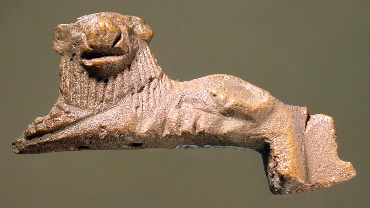 Statuette eines gelagerten Löwen, Kopf en face drehend, Beschlag eines Geräts oder Gefäßes; sehr dunkle Patina