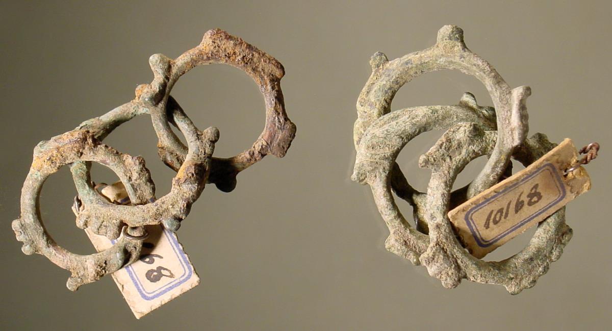 Zweimal je drei kleine miteinander verbundene Ringe mit hervorspringenden Verzierungen