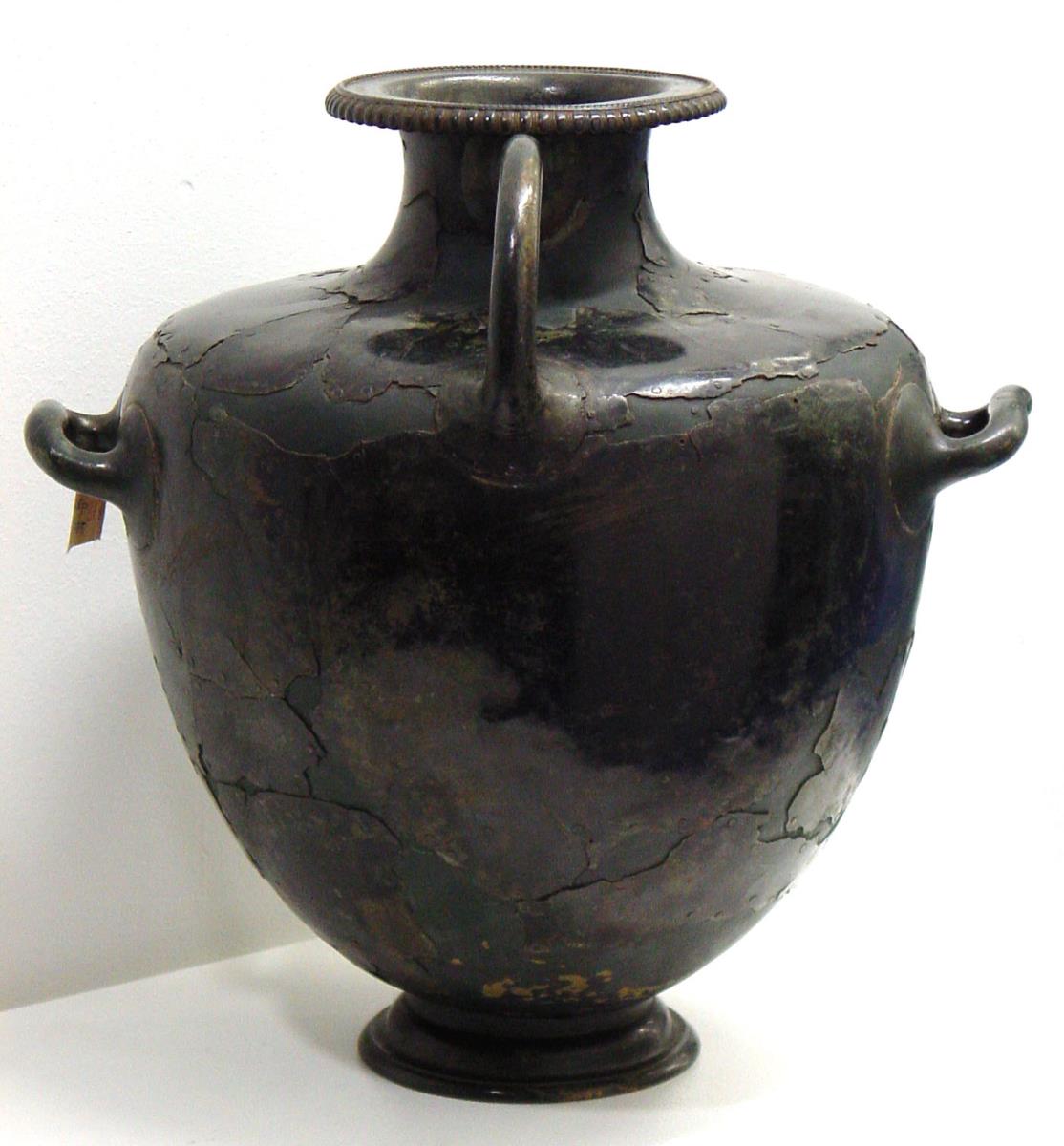 Hydria, aus Fragmenten mittels Nieten auf einer Unterlage zusammengesetzt. Auf dem Mündungsrand die eingeschlagene griechische Inschrift: ΑΘΛΟΝ ΕΓ ΛΑΜΨΑΚΟ ΕΠΙ ΛΕΩΦΑΝΤΟ ΤΟ ΛΑΜΠΡΟ