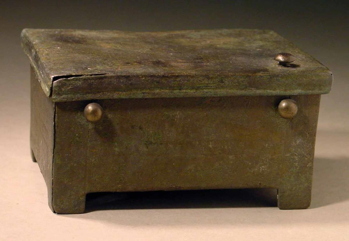 Viereckiges Kästchen mit Deckel und Scharnier. Auf dem Deckel in Relief das Vorderteil eines Stieres, der zwar beim Ankauf nicht auf dem Deckel saß, nach Angabe des Verkäufers aber ursprünglich dorthin gehörte. Er ist deshalb jetzt wieder darauf befestigt worden.