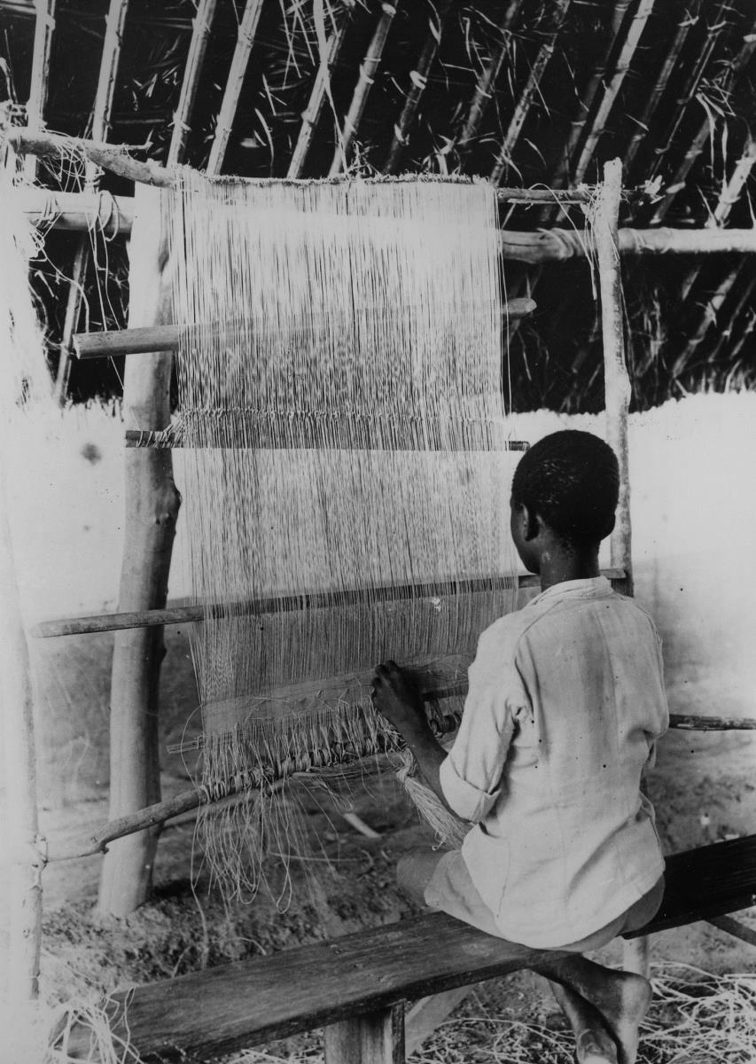 Man. Jeune tisserand fabriquant un tapis de raphia