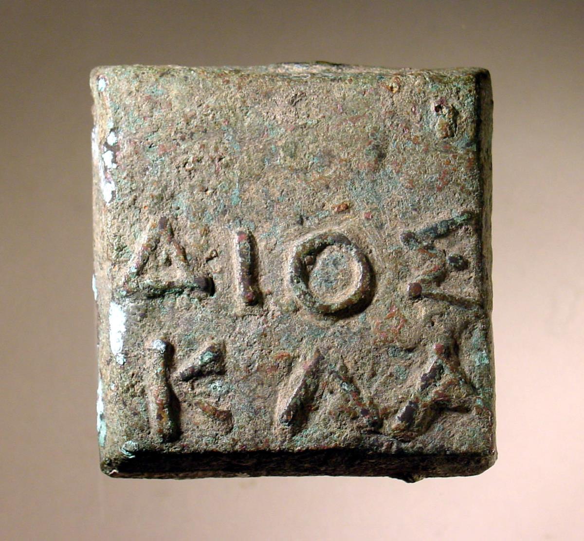 Einstufiges quadratisches Gewicht mit griechischer Inschrift: ΔΙΟΣ / ΚΛΑ