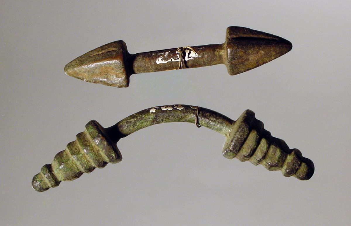 Zwei stangenförmige, knopfartig auslaufende Geräte (Mantelschließen)