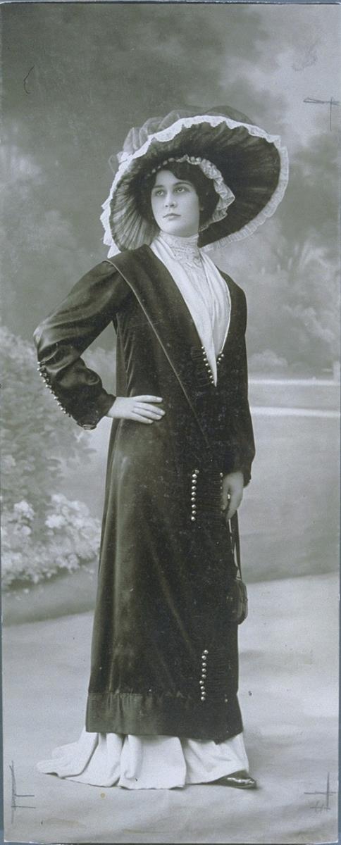 Frau in Kleid und Mantel mit Hut