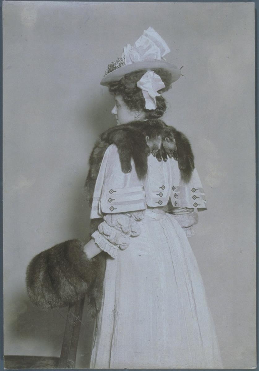 Frau in Kleid und Pelzstola mit Muff