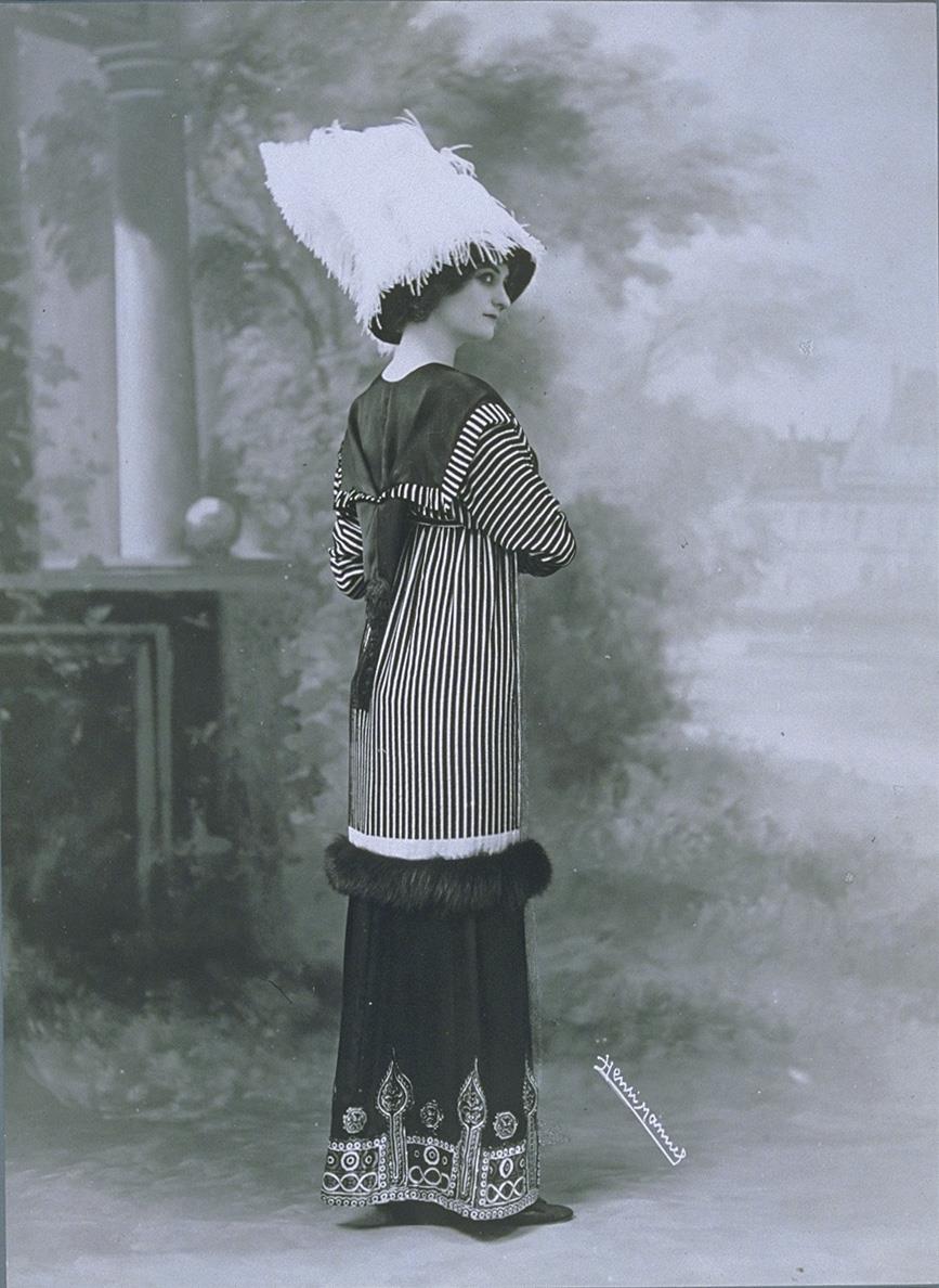 Frau in Jacke und Rock mit Hut von Margaine-Lacroix