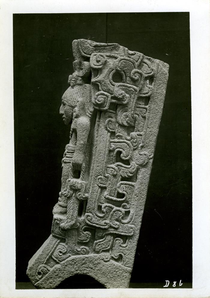 Seitenansicht einer Steinfigur, oberer Teil abgebrochen, Seitenteile mit reicher stilisierter Ornamentik. Sammlung Guillermo de Heredia.