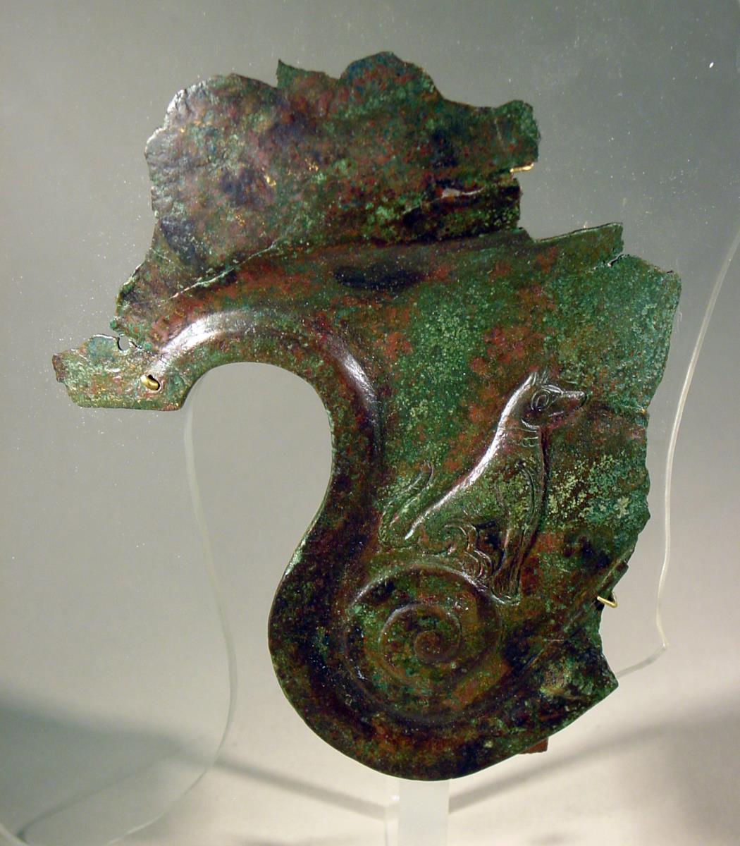 Fragment eines Helms mit sitzendem Hund