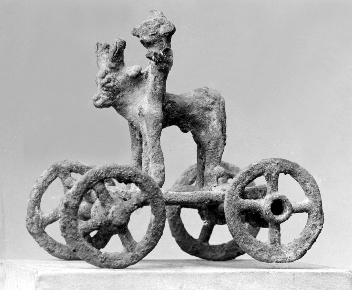 Primitive Statuettengruppe eines stehenden, nackten Mannes mit Stier auf einem vierrädrigen Wagen