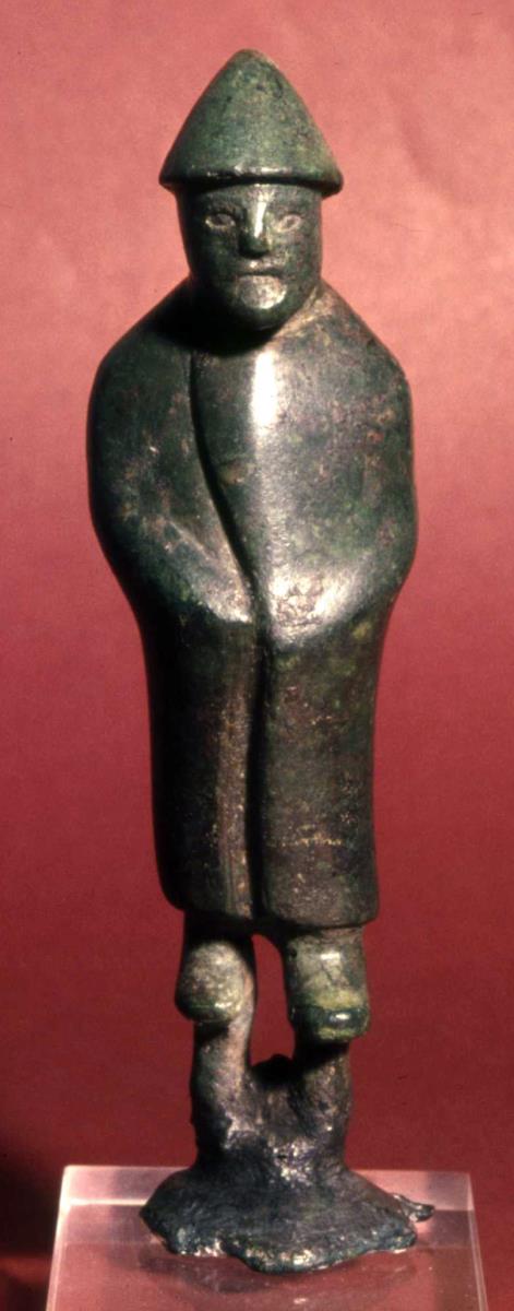 Archaische Votivstatuette eines stehenen, in einen dicken Mantel eingewickelten Mannes