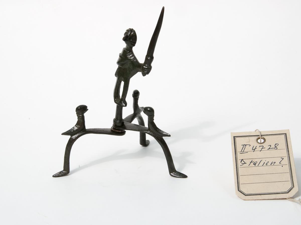 Männliche Figur auf Dreifuß
