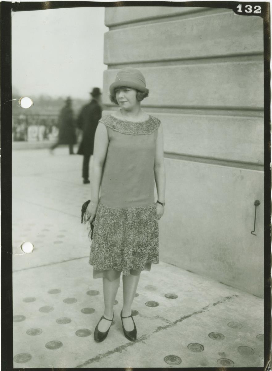 Frau in Kleid und Mantel auf dem Rennplatz