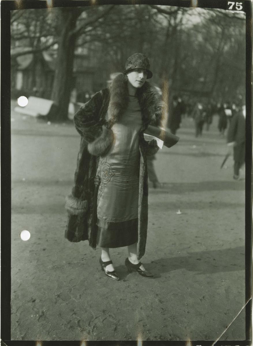 Frau in Kleid und Mantel auf dem Rennplatz