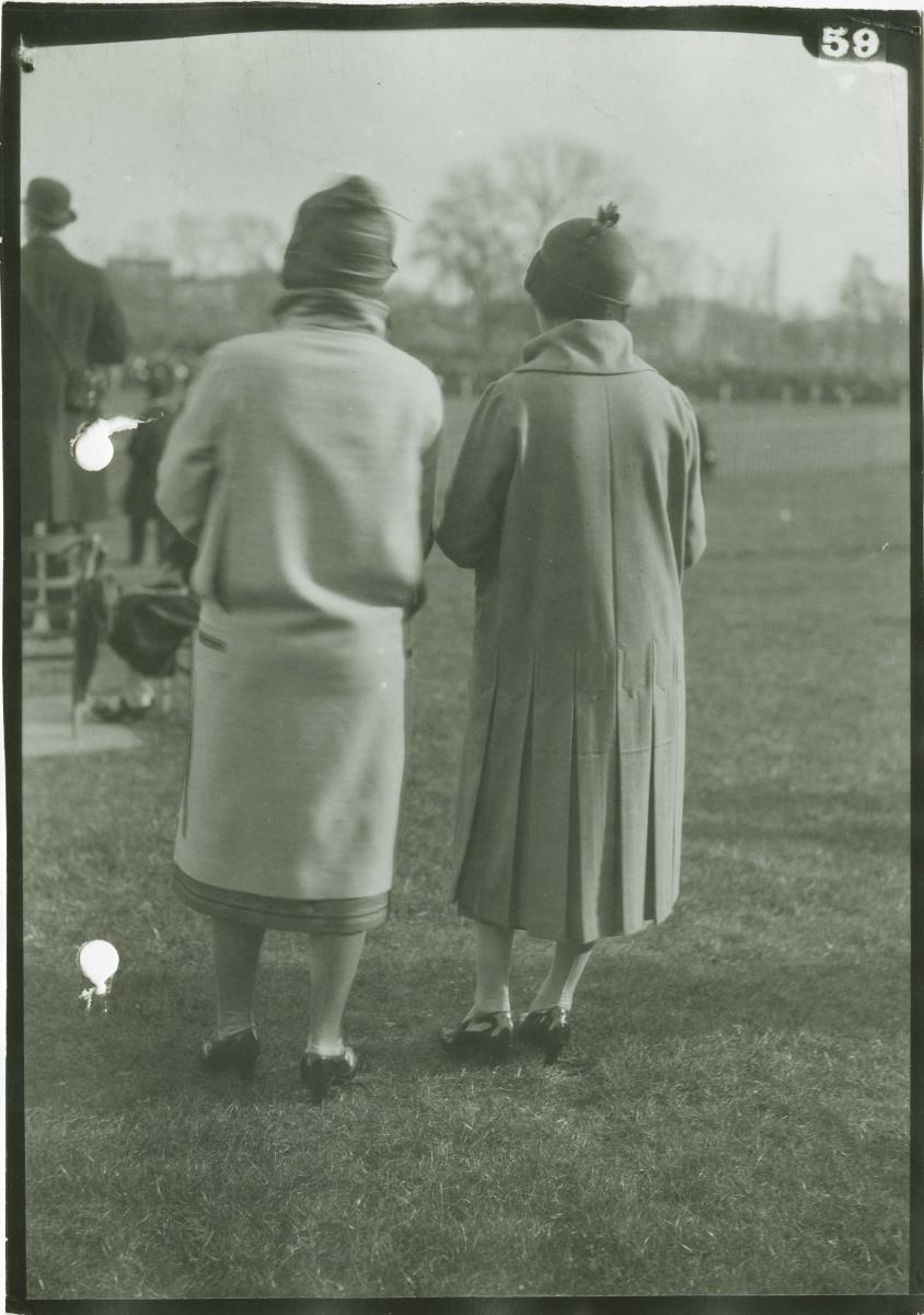 Frauen in Mänteln auf dem Rennplatz