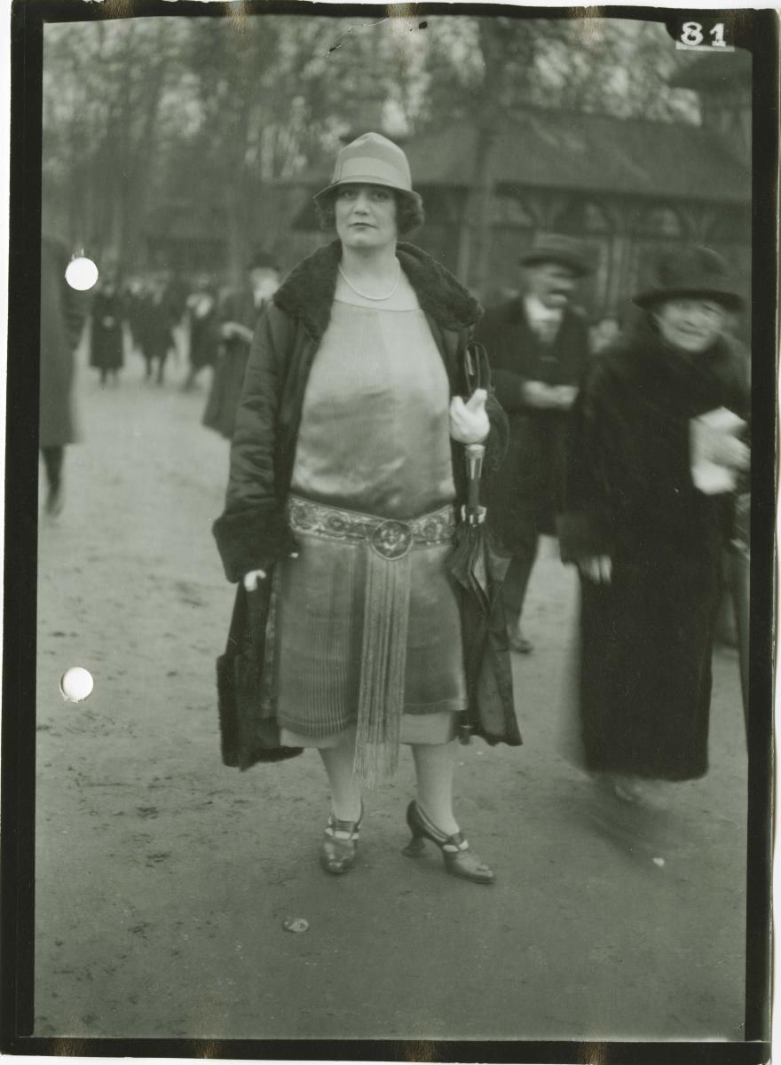 Frau in Kleid und Mantel auf dem Rennplatz
