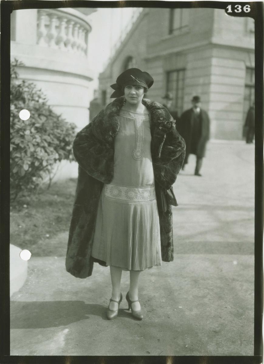Frau in Kleid und Mantel auf dem Rennplatz