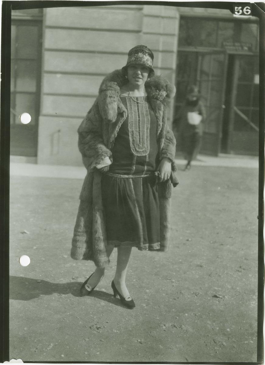 Frau in Kleid und Mantel auf dem Rennplatz