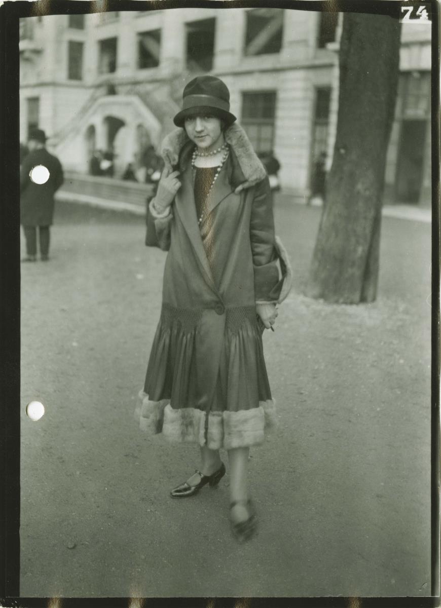 Frau in Kleid und Mantel auf dem Rennplatz