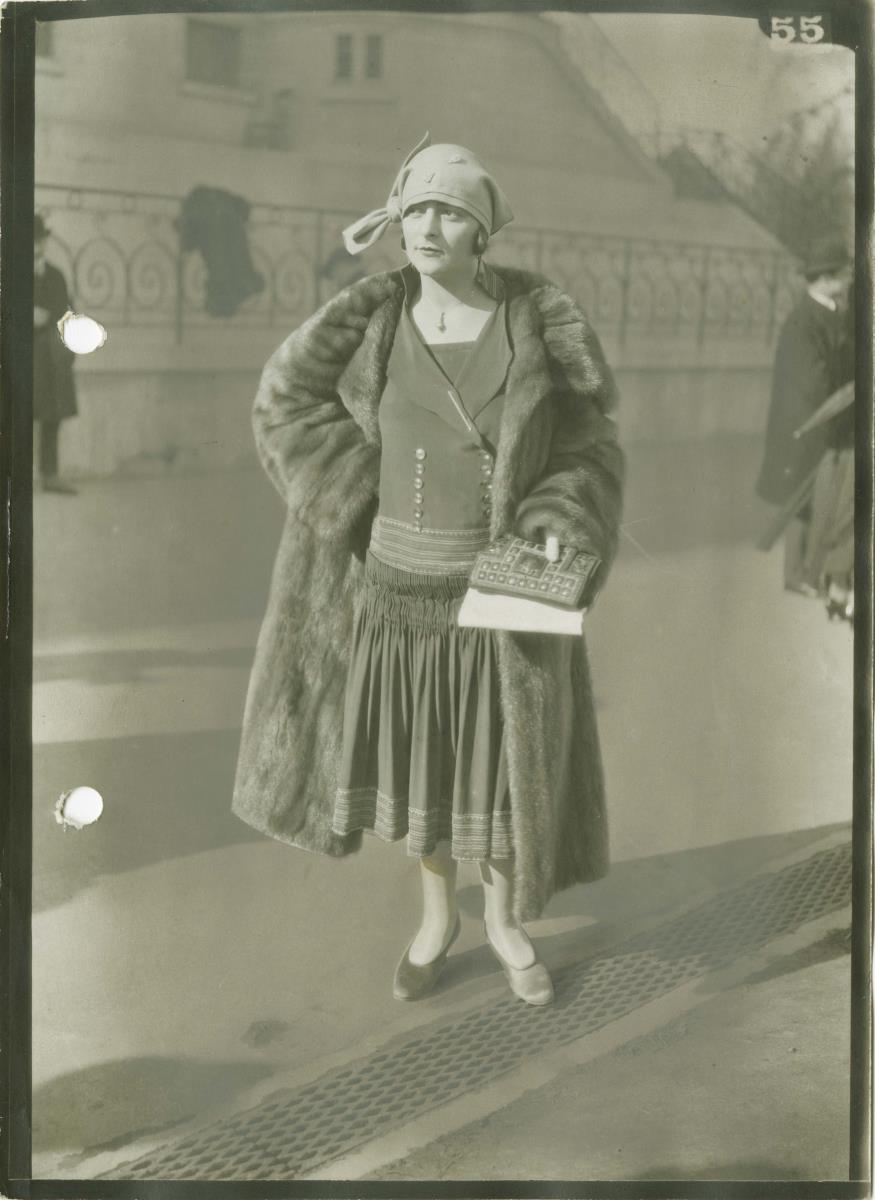 Frau in Kleid und Mantel auf dem Rennplatz