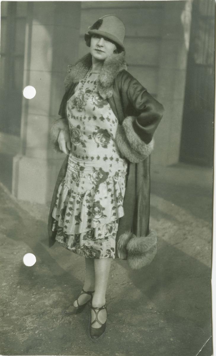 Frau in Kleid und Mantel auf dem Rennplatz