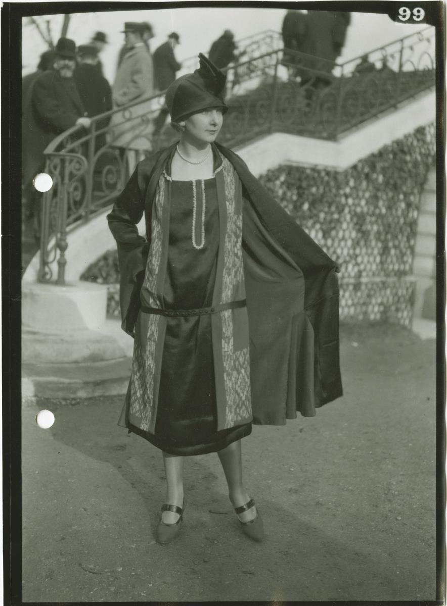 Frau in Kleid und Mantel auf dem Rennplatz