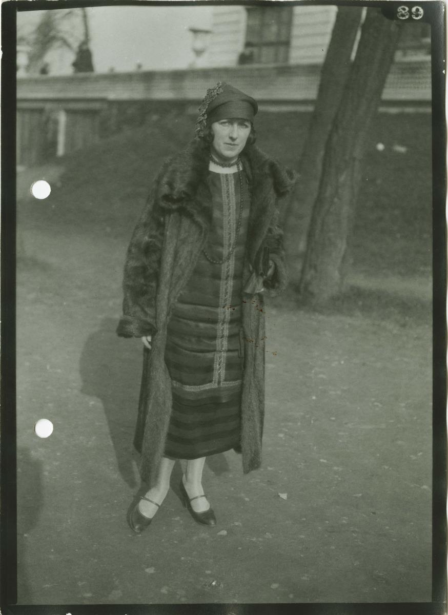 Frau in Kleid und Mantel auf dem Rennplatz