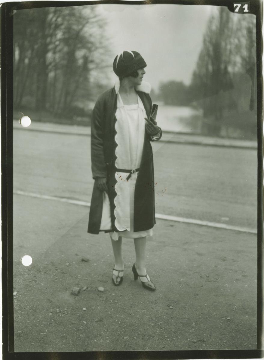 Frau in Kleid und Mantel auf dem Rennplatz