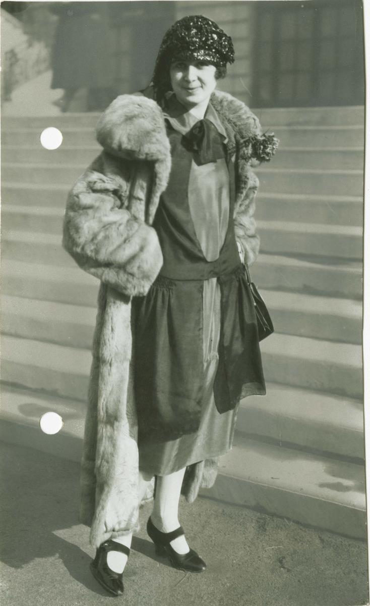 Frau in Kleid und Mantel auf dem Rennplatz