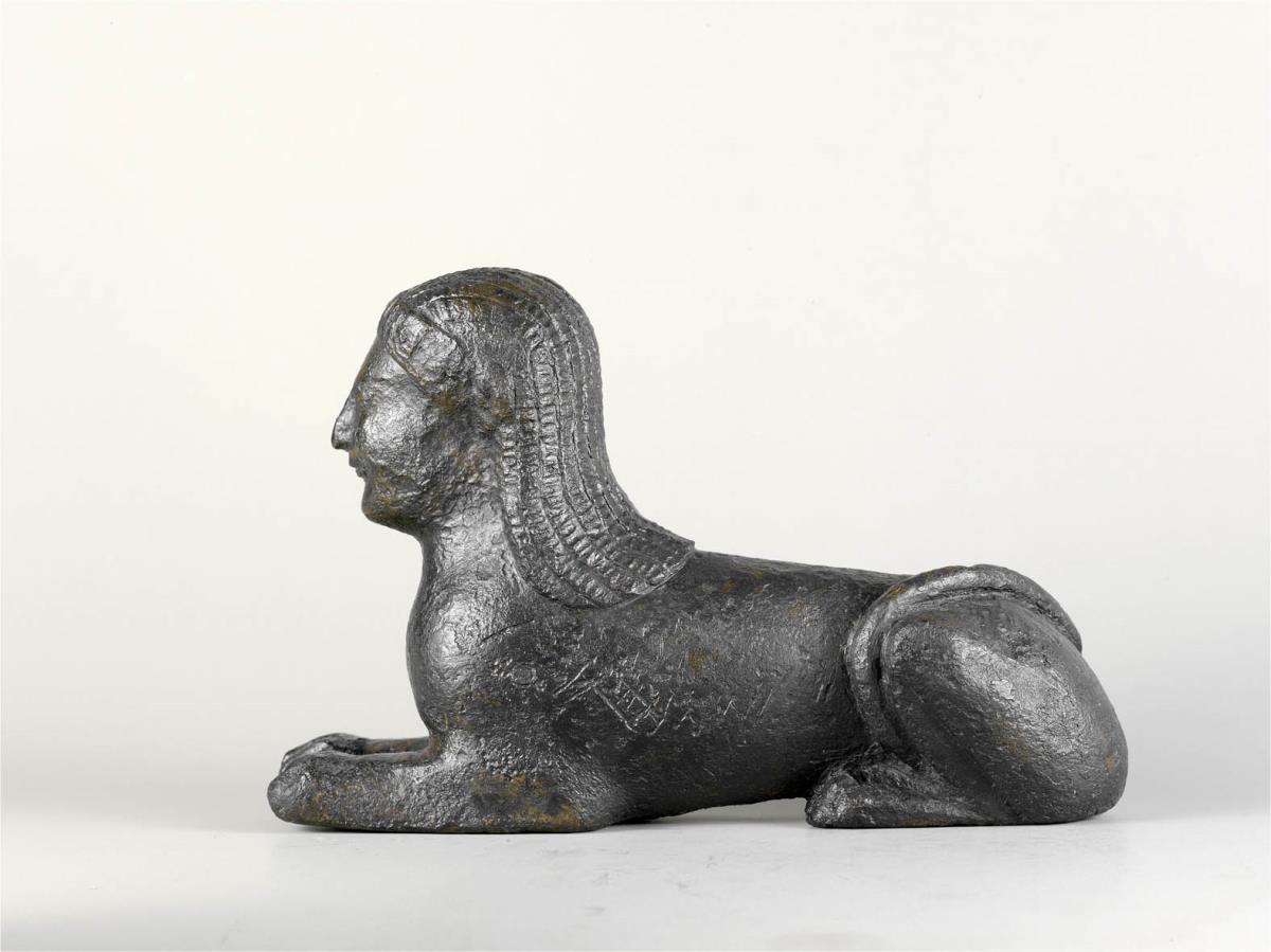Liegende Sphinx, dickwandiger Guss, Kopf massiv, Kernmasse entfernt, Kernstützen sichtbar, ..., reduziert