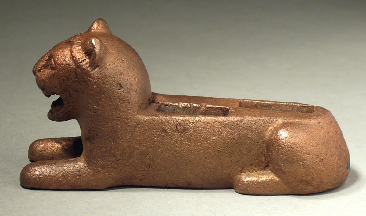 Liegender Löwe, wohl Basis für eine Statuette mit vorgesetztem linken Bein, Einlasslöcher sehr sorgfältig, das vordere mit Nieten seitlich