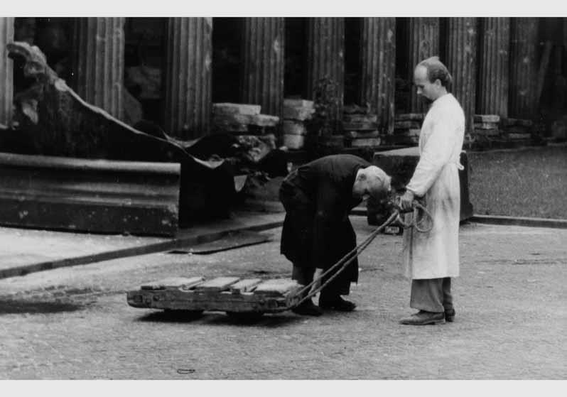 Rudolph Kuhn und ein Mitarbeiter bei Transportarbeiten vor dem Hintergund der zum Teil zerstörten Kolonnaden auf der Museumsinsel
