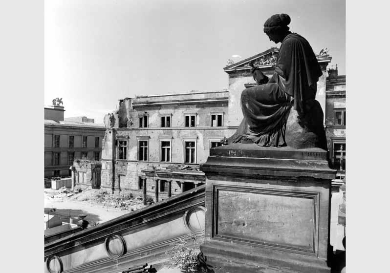 Blick auf die Sandsteinfigur von Karl Adalbert Moser an der Freitreppe der Nationalgalerie vor dem Hintergrund des zum Teil zerstörten Neuen Museums und des Alten Museums