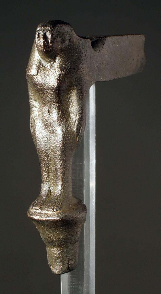 Teil eines Geräts oder Möbels, ägyptisch. Weibliche Gestalt, nackt (?) mit anliegenden Armen, Augen waren offensichtlich eingelegt, hinten Schiene, ziemlich dünn gegossen, reduziert