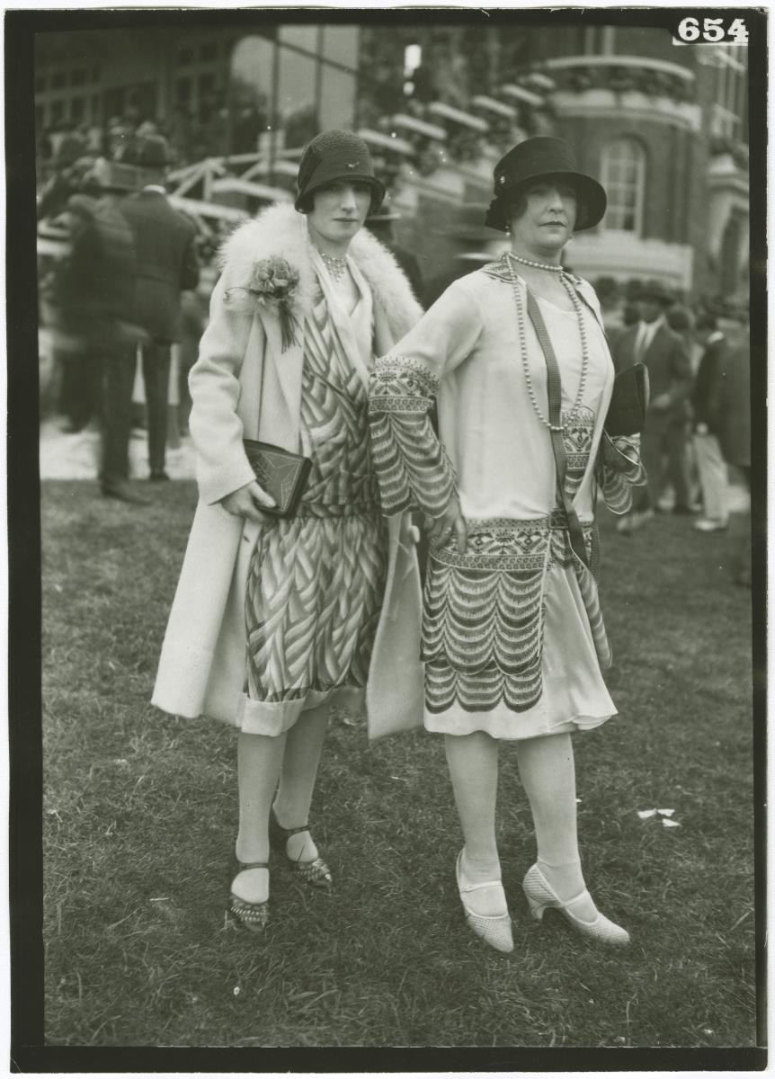 Frau in Kleid und Mantel und Frau in Ensemble auf dem Rennplatz in Deauville