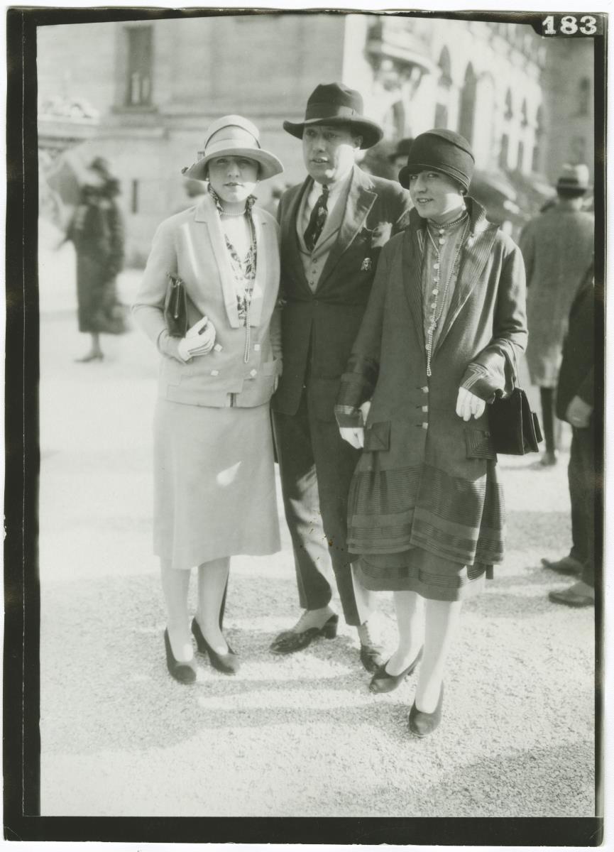 Frauen in Kostümen und Mann in Anzug auf dem Rennplatz in Longchamp