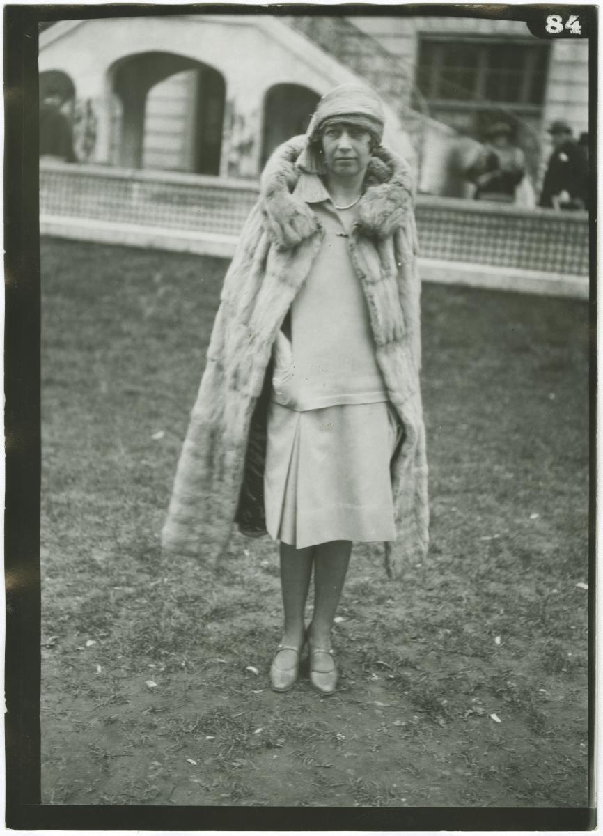 Frau in Kleid und Mantel auf dem Rennplatz in Auteuil