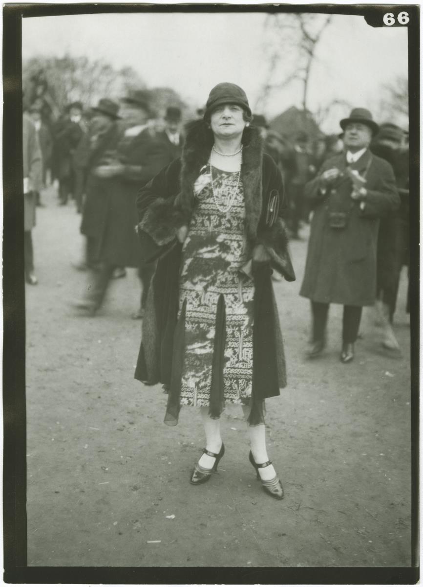 Frau in Kleid und Mantel auf dem Rennplatz in Auteuil