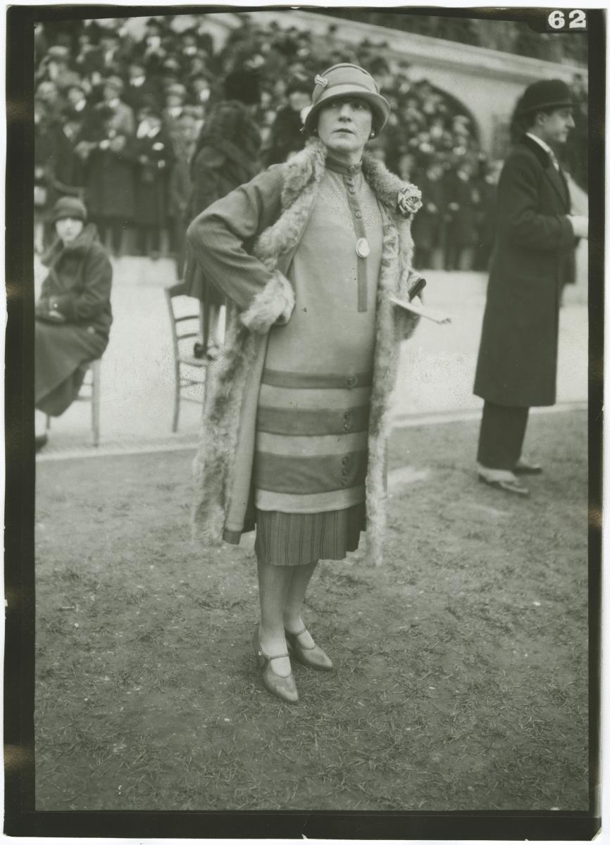 Frau in Kleid und Mantel auf dem Rennplatz in Auteuil