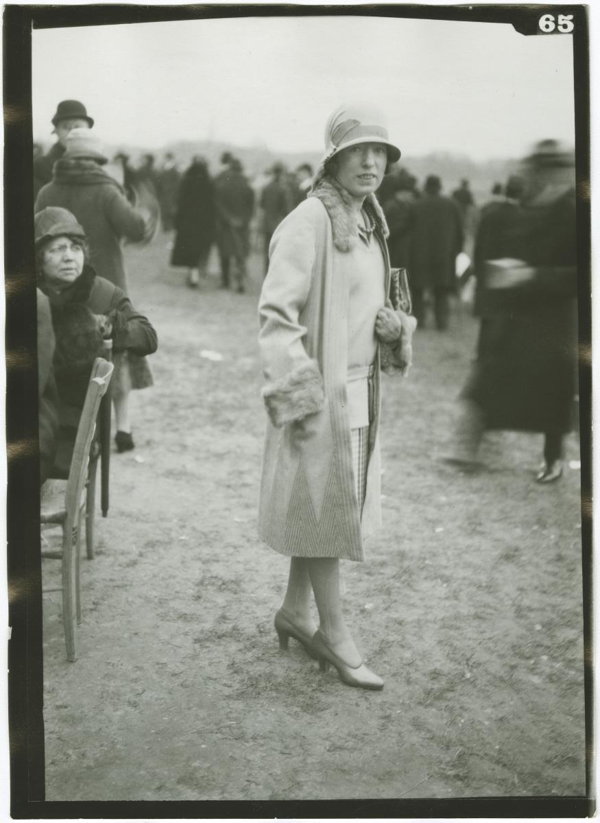 Frau in Kleid und Mantel auf dem Rennplatz in Auteuil