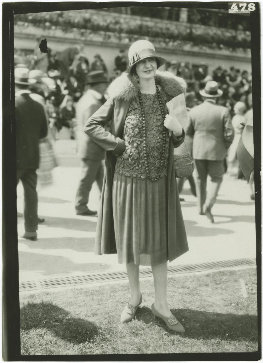 Frau in Kleid und Mantel auf dem Rennplatz in Auteuil