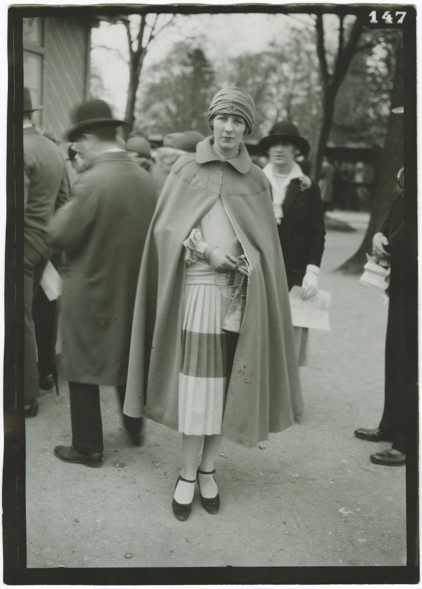 Frau in Kleid und Mantel auf dem Rennplatz in Auteuil