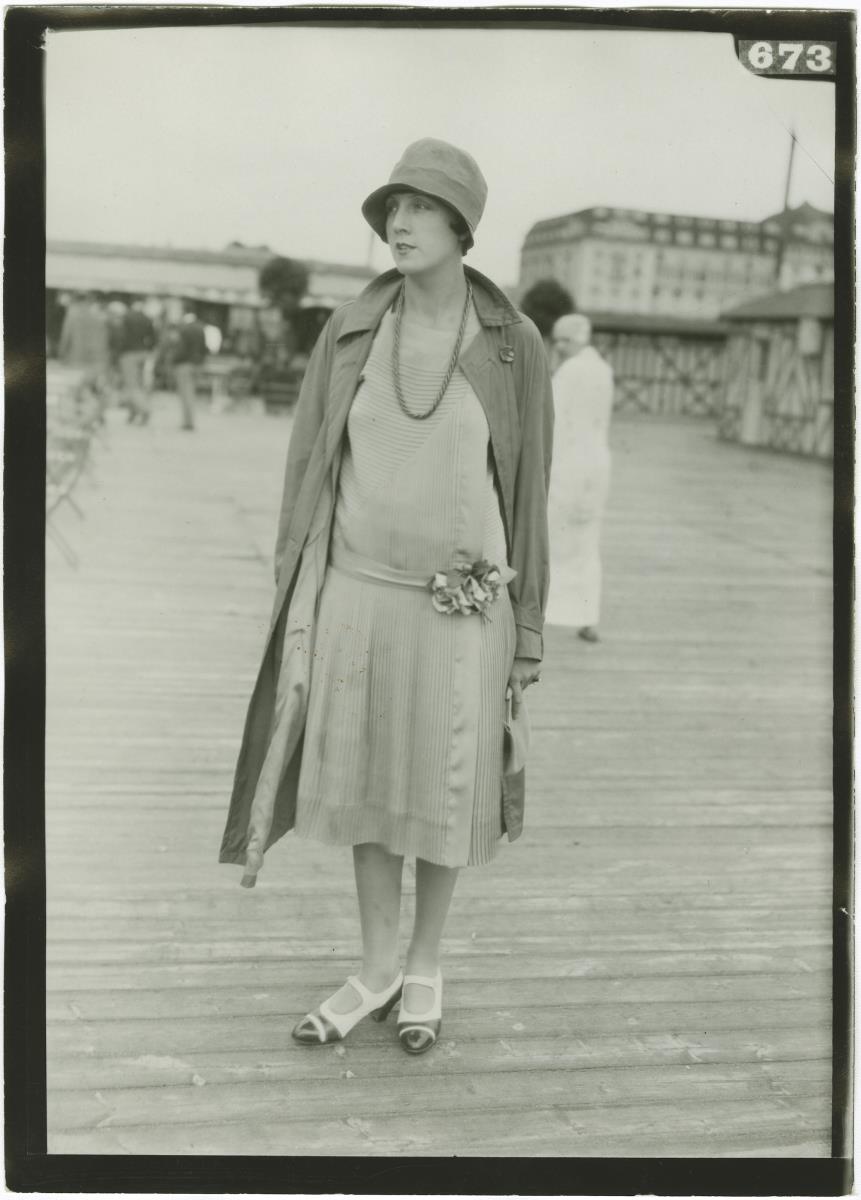 Frau in Kleid und Mantel auf dem Rennplatz in Deauville